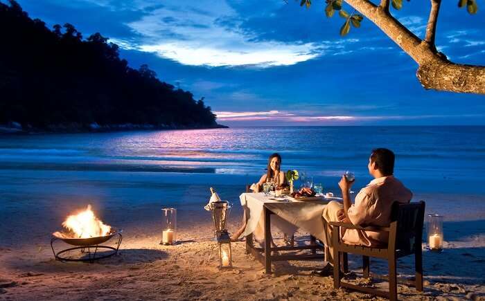Couple enjoying a surprise and romantic dinner by the beach
