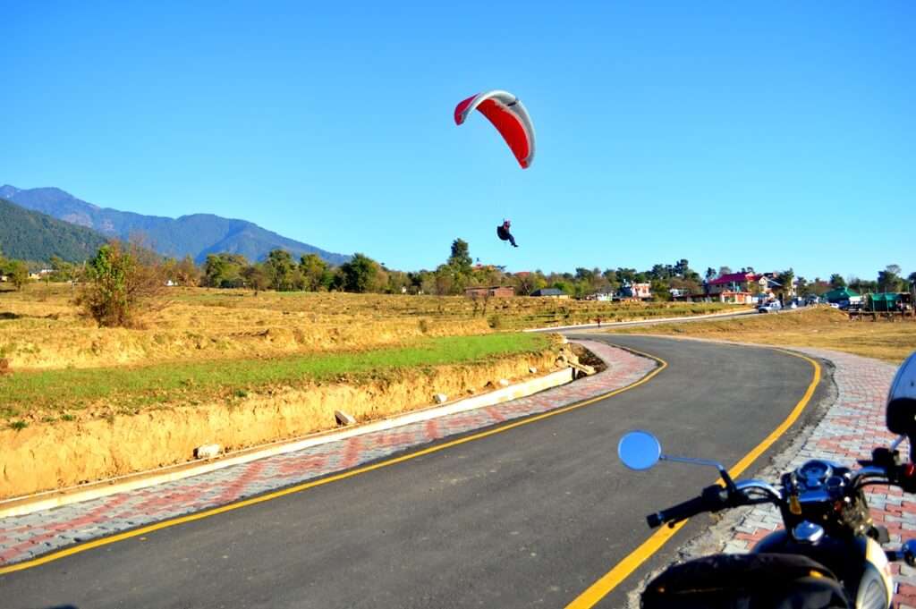 a guy landing on road after paragliding