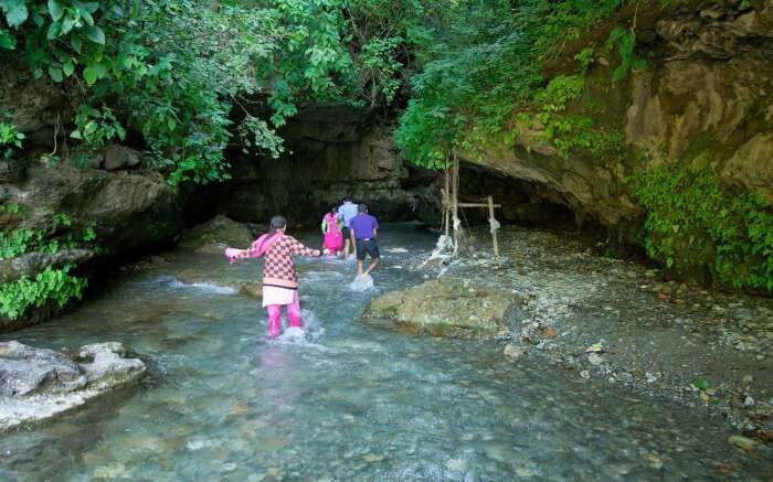 people crossing a stream to go to Robbers cave