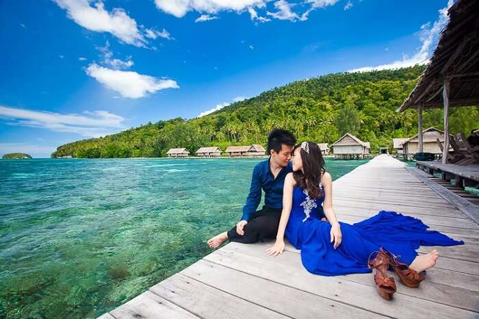 Romantic couple sitting by the beach in Raja Ampat Islands