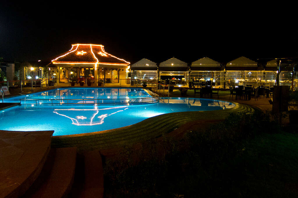 an outdoor poor with a villa resort decorated with lights