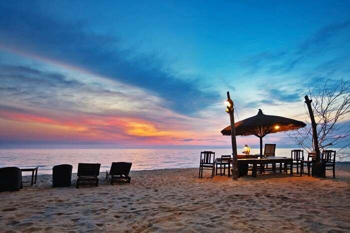 Wooden chairs and umbrellas on white beach in sunset time at Phu Quoc island in Vietnam