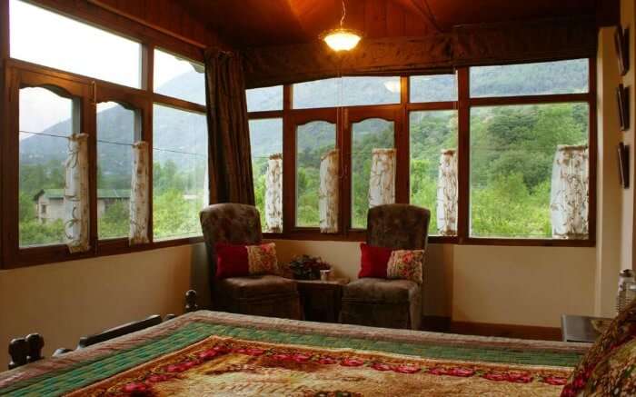 A cozy room with windows in Our Place Himalayas - a popular farmstay in Manali 