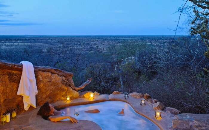 A woman in an outdoor jacuzzi in a honeymoon lodge in South Africa 