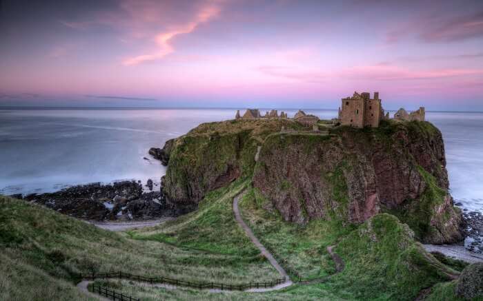Dunnottar Castle with pink tinged sky in backdrop