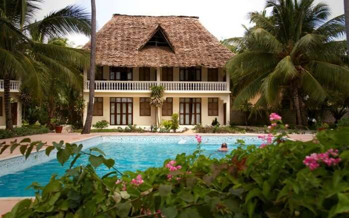 a Zanzibari thatched roof villa with a pool 