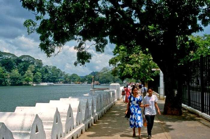 Tourists taking a leisure walk by the Kandy Lake in Sri Lanka