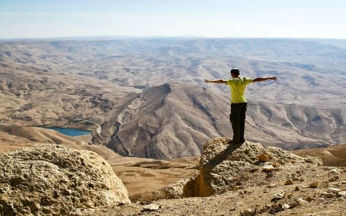 A tourists standing at the edge of a cliff in the mountains of Jordan 