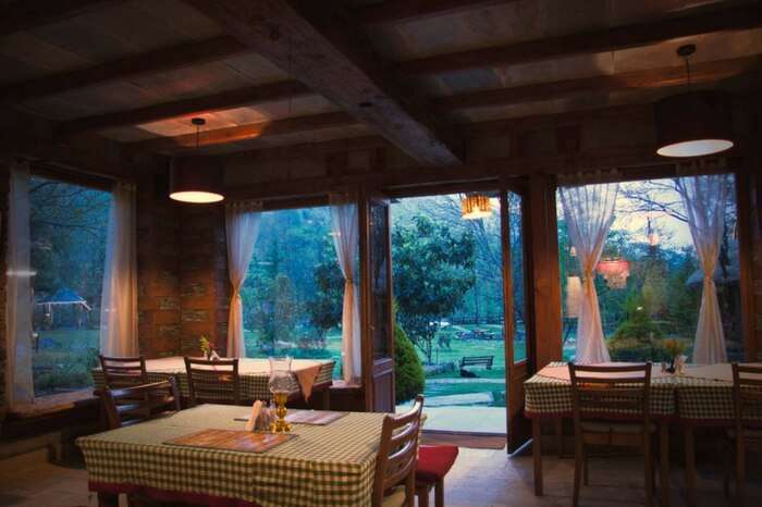 A view of dining space of Neeralaya Hotel overlooking garden area in Manali
