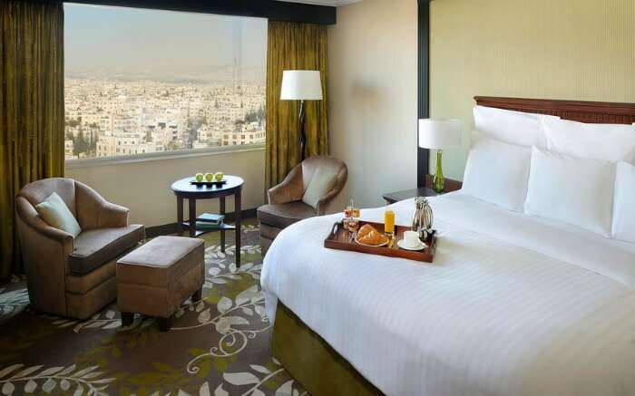 breakfast tray on a hotel bed and a window offering city views