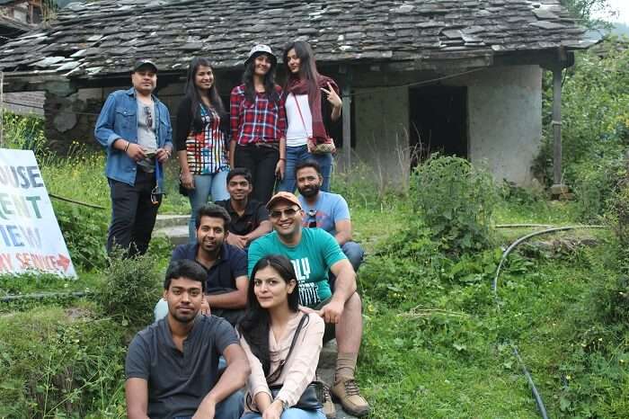 A bunch of travelers relaxing outside a rustic hut in Kasol