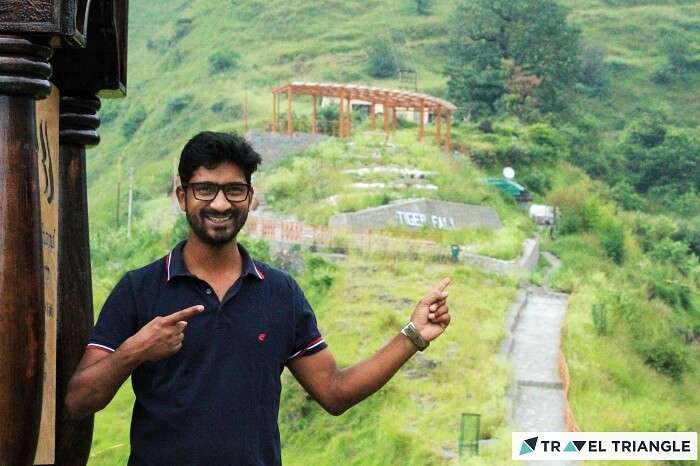 A traveler points out towards the top point of Tiger Fall in Chakrata