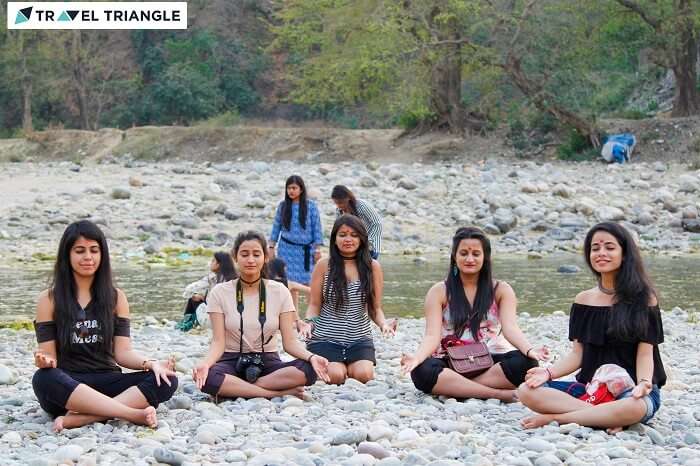 A group of girls posing in the meditation pose by the banks of the Kosi river in Jim Corbett