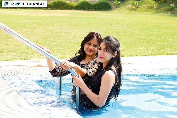 Two girls enjoying in a swimming pool at a resort in Jim Corbett