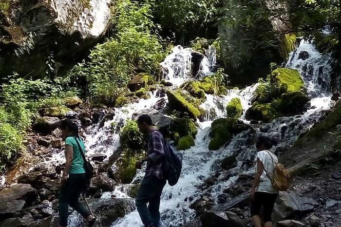 Travelers walking past the waterfall in Tosh