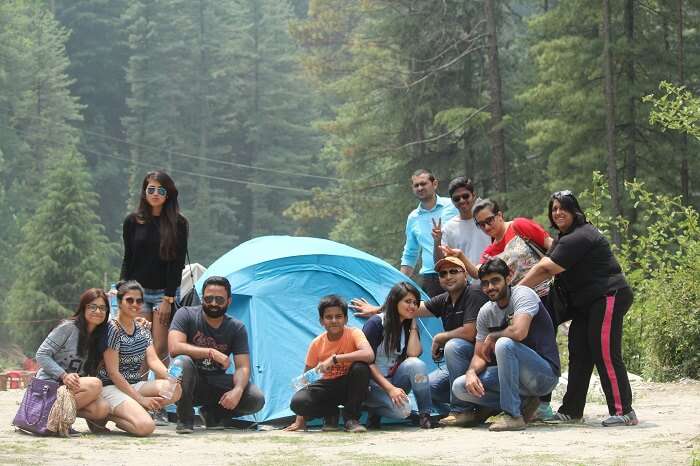 A group of travelers on one of the weekend trips from Delhi to Mcleodganj and Triund pose next a camp at the campsite