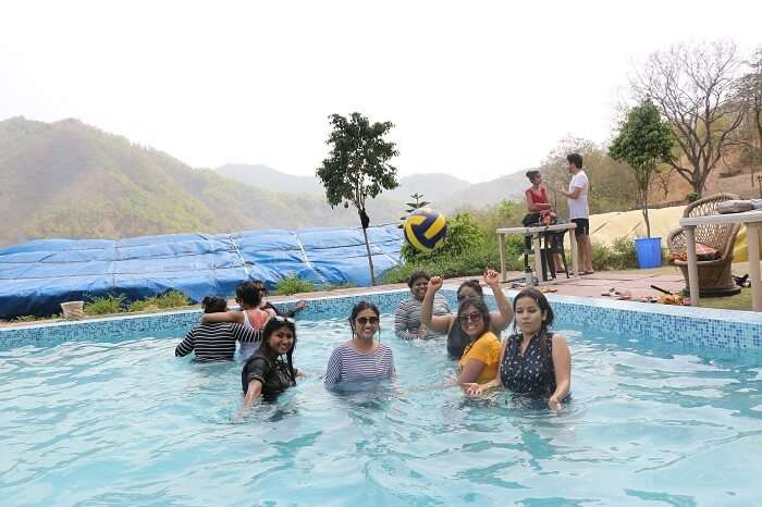 Travelers on their weekend trip to Rishikesh enjoying in a swimming pool in the camp resort