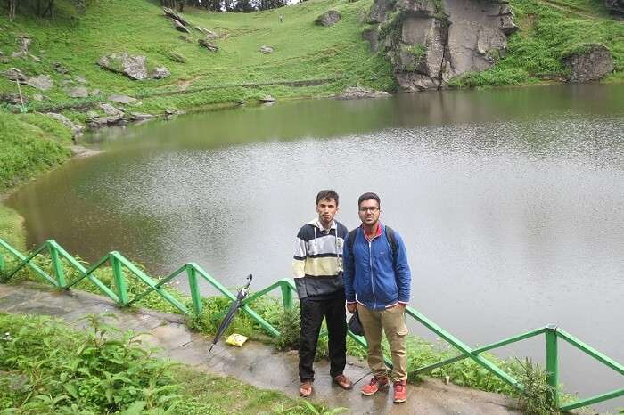 Two travelers standing next to a famous lake in Tirthan Valley