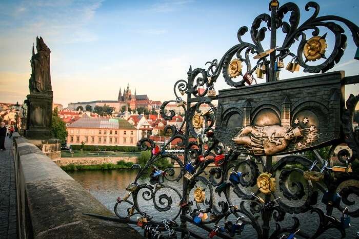 Love locks on the Charles Bridge in Prague at sunrise with Prague Castle in the background