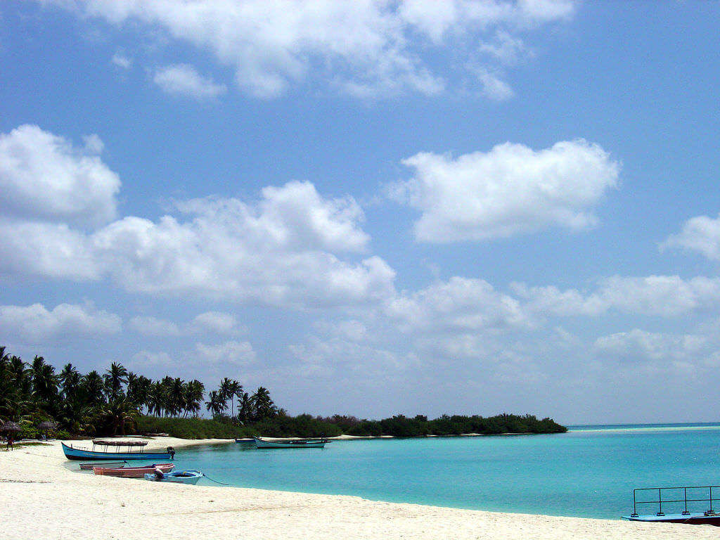 लक्षद्वीप पर्यटन स्थल बंगाराम द्वीप सफेद रेतीले समुद्र तट पर एक नाव