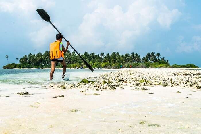 A child on Kalpeni beach with kayak paddle