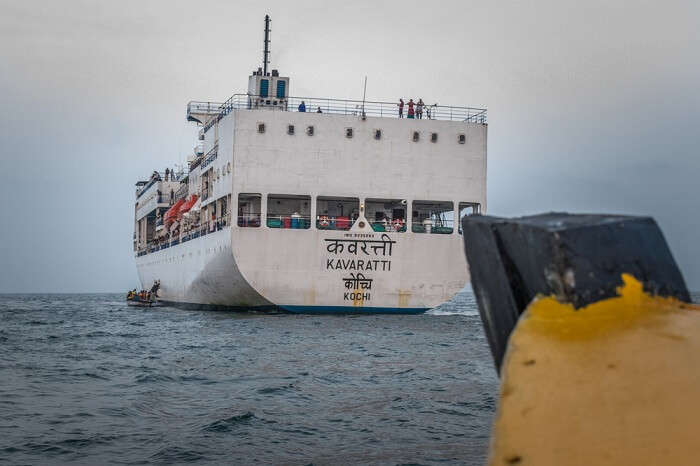 Wooden fishing boat heading towards cruise ship Kavaratti