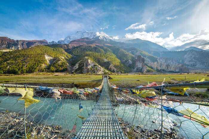 prayer flags tied to a bridge in the hills of Annapurna