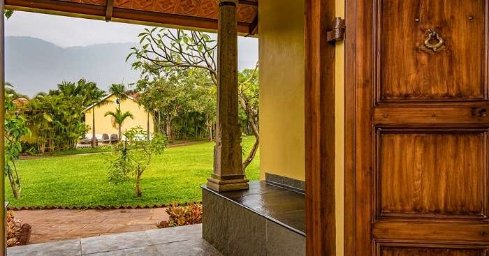 A shot of the lawn and cottages from inside another cottage at Dvara Siruvani Resort in Coimbatore