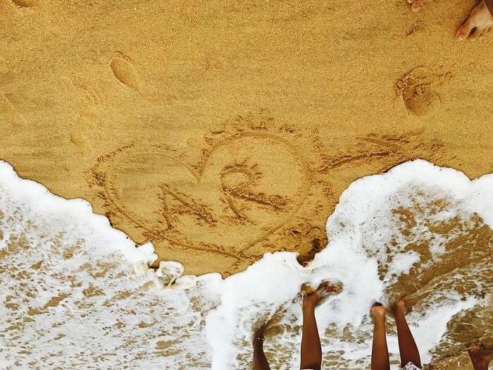 aarti and revan writing name on beach in kovalam, kerala