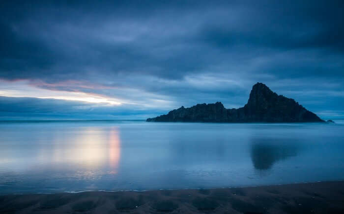 The quiet waters at Karekare Beach in Auckland at sunset 