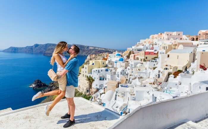 Young couple looks down on the landscape of the island of Santorini 