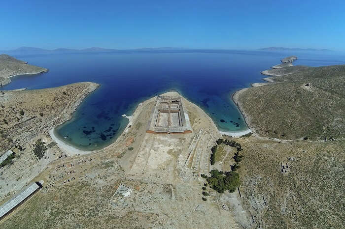 An aerial shot of the island of Gyaros in Greece along with the azure waters surrounding it