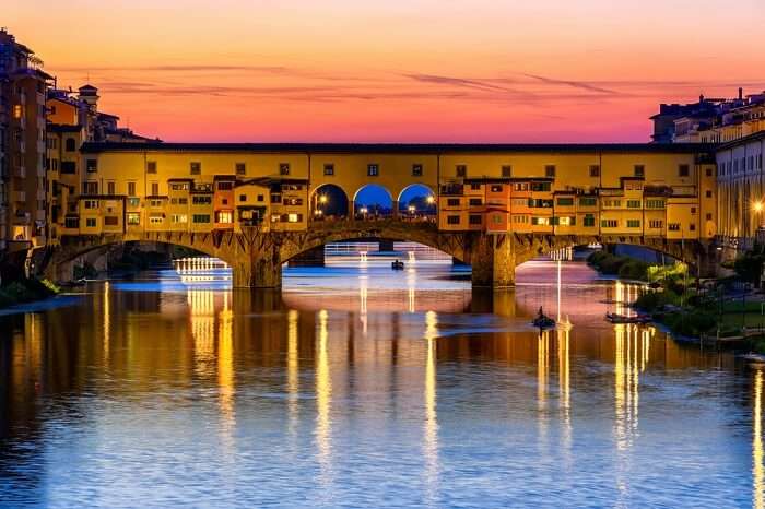 Saulėlydžio vaizdas į Ponte Vecchio tiltą virš Arno upės Florencijoje