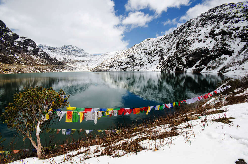 prayer flags tides across trees near a beautiful lake