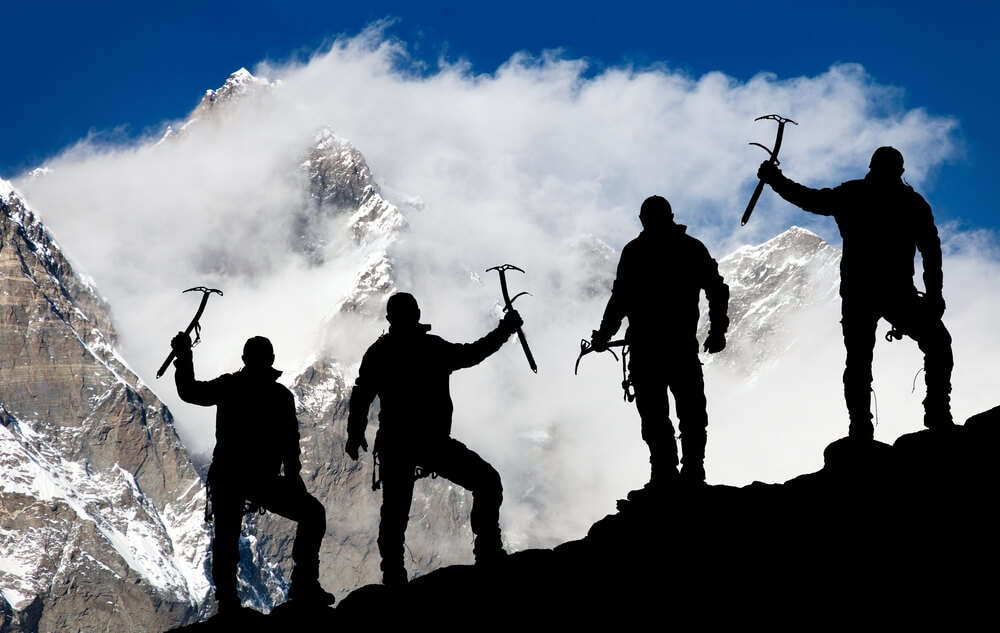 three men holding trekking equipment