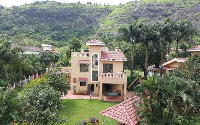 A view of Aashiyana Villa in Lonavala surrounded by hills and plantation