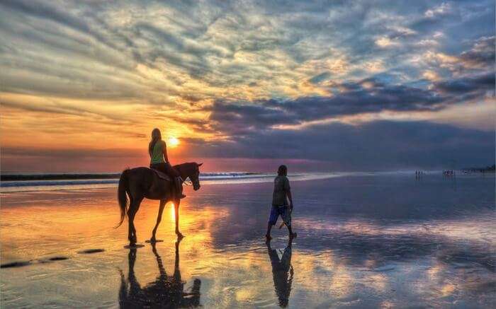 A woman riding a horse by the ocean near Canggu Beach