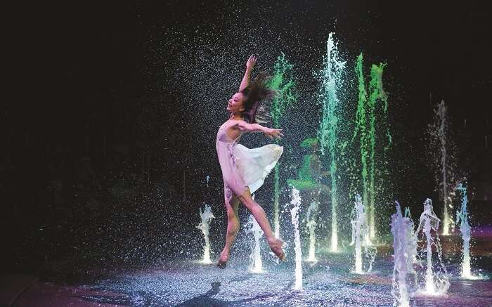 A girl dancing as colourful fountains erupt