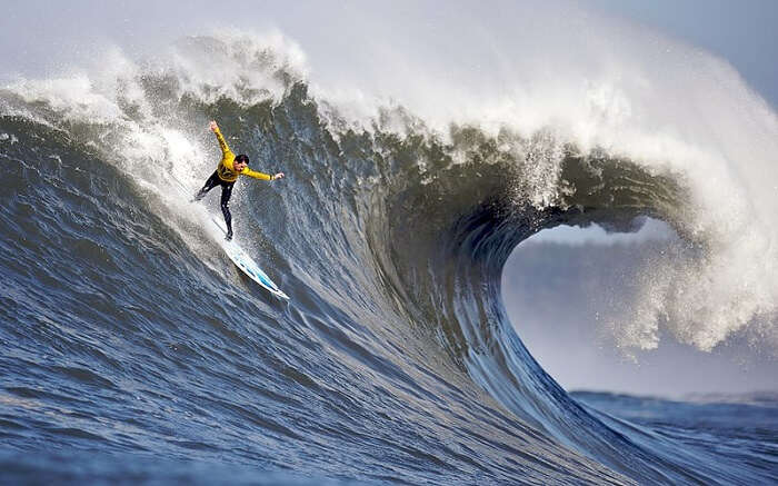 A man wearing yellow clothes surfing in high tides 