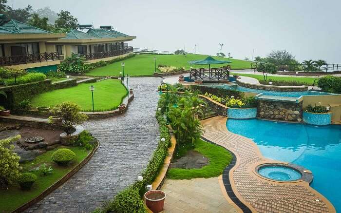A resort with an outdoor pool and lush lawns 