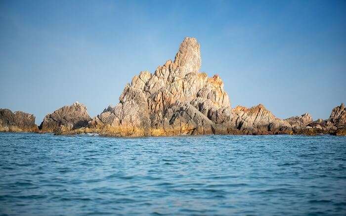 A small rock mountain in ocean 