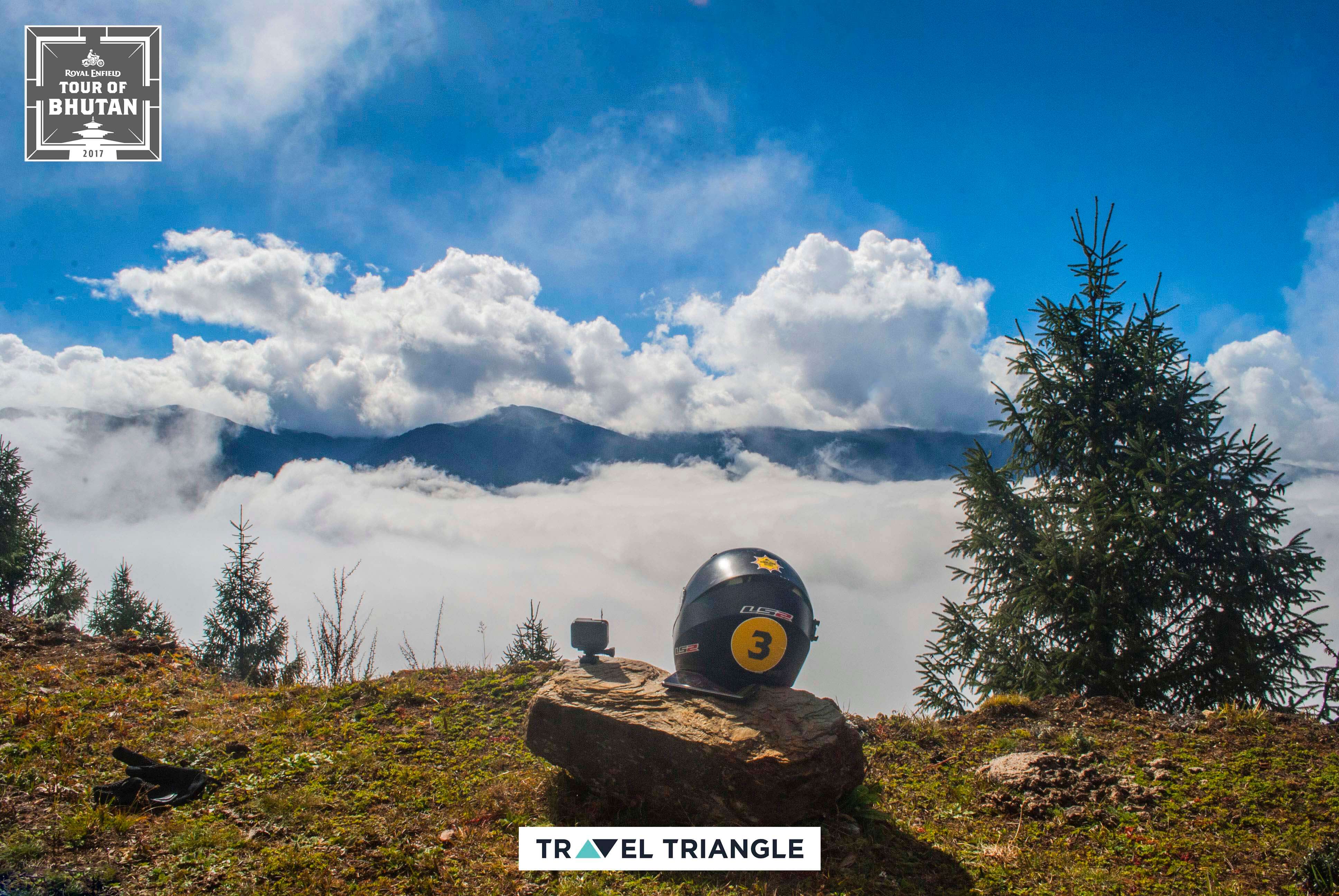royal enfield india bhutan road trip: a bike helmet and clouds beyond it on the hill