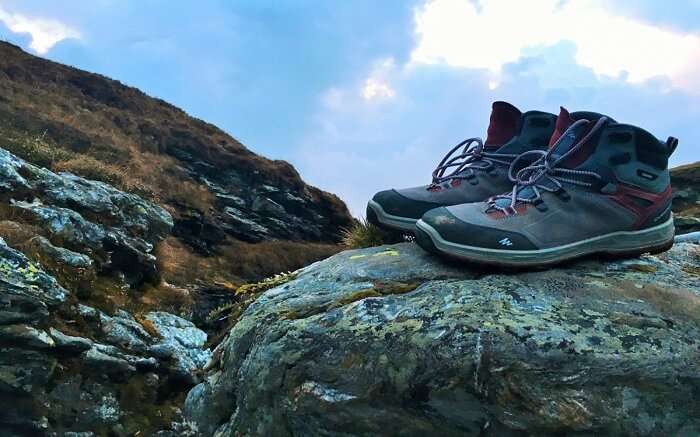 Trekking shoes kept on a boulder overlooking mountains