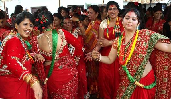 married women wearing red sarees and dancing