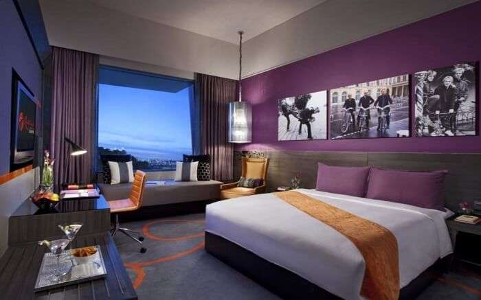 A king size bed and a huge glass window in a hotel room 