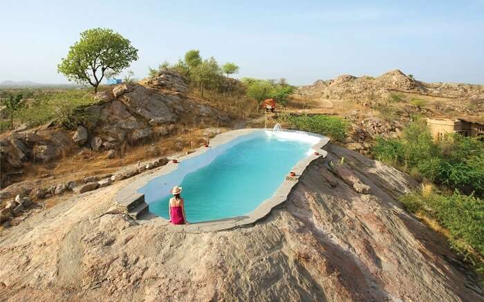 A woman sitting beside the rock-cut pool of Lakshman Resort 