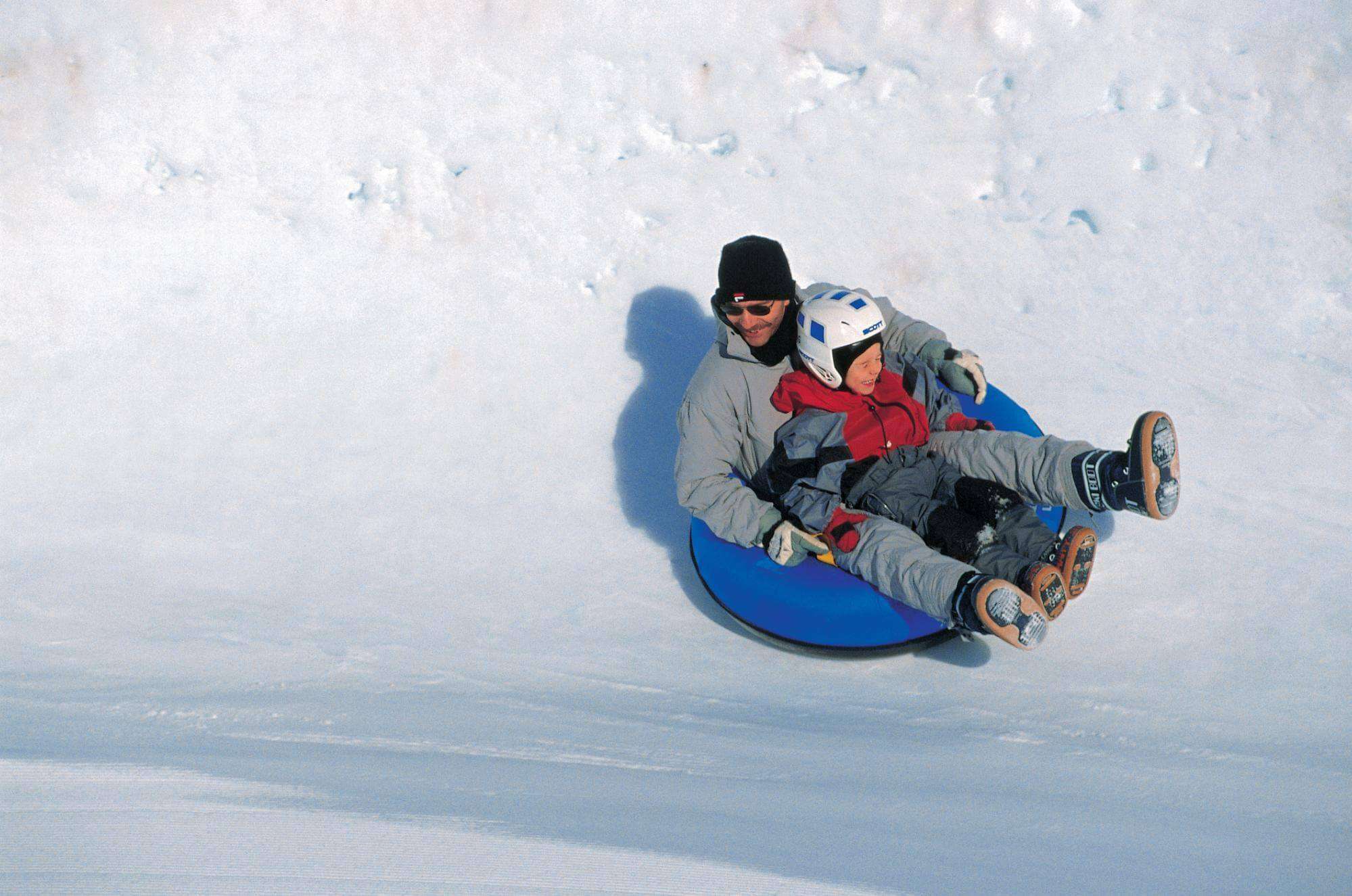 a man a kid playing tobogganing