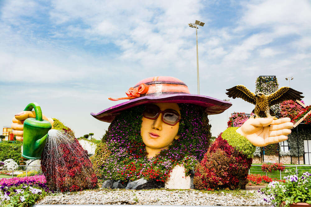 a structure of a lady wearing hat covered by flowers
