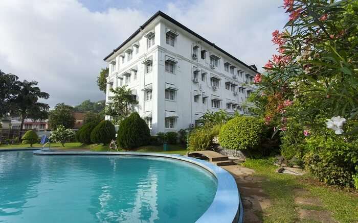 a white painted hotel with an outdoor pool 