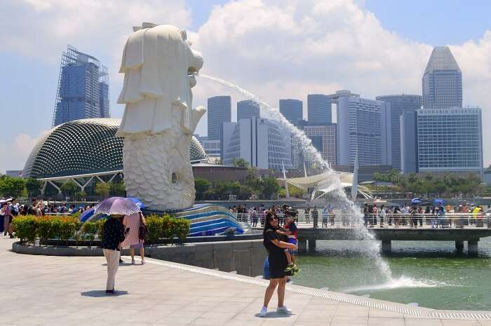 anshu singapore trip: anshu and son posing near merlion